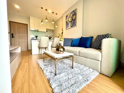 Modern living room with elegant decor and open kitchen layout, featuring cozy seating and stylish lighting.