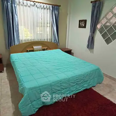 Cozy bedroom with teal bedding and natural light, perfect for relaxation.
