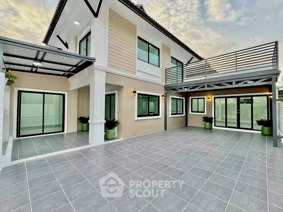 Modern two-story house with spacious tiled courtyard and large windows.