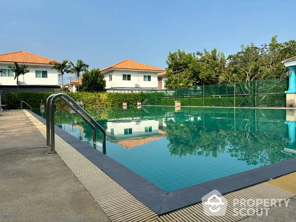 Stunning residential pool area with clear blue water and lush greenery, perfect for relaxation and leisure.