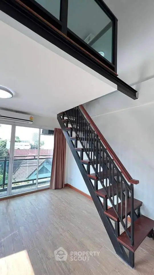 Modern loft apartment with stylish staircase and large windows offering natural light and scenic views.