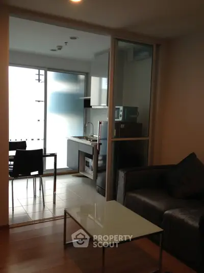 Modern apartment with open kitchen and cozy living area, featuring sleek furniture and natural light.