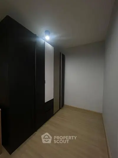 Minimalist storage room with sleek black wardrobes and modern lighting.