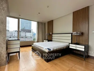 Luxurious bedroom with modern furnishings and city view, featuring elegant wood flooring and large windows.