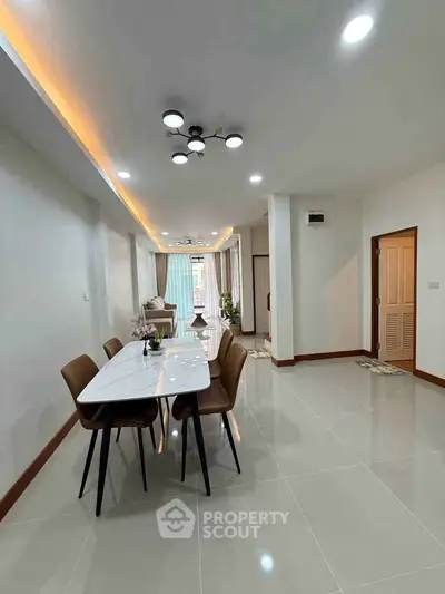 Spacious modern dining area with elegant lighting and sleek furniture in a contemporary home.