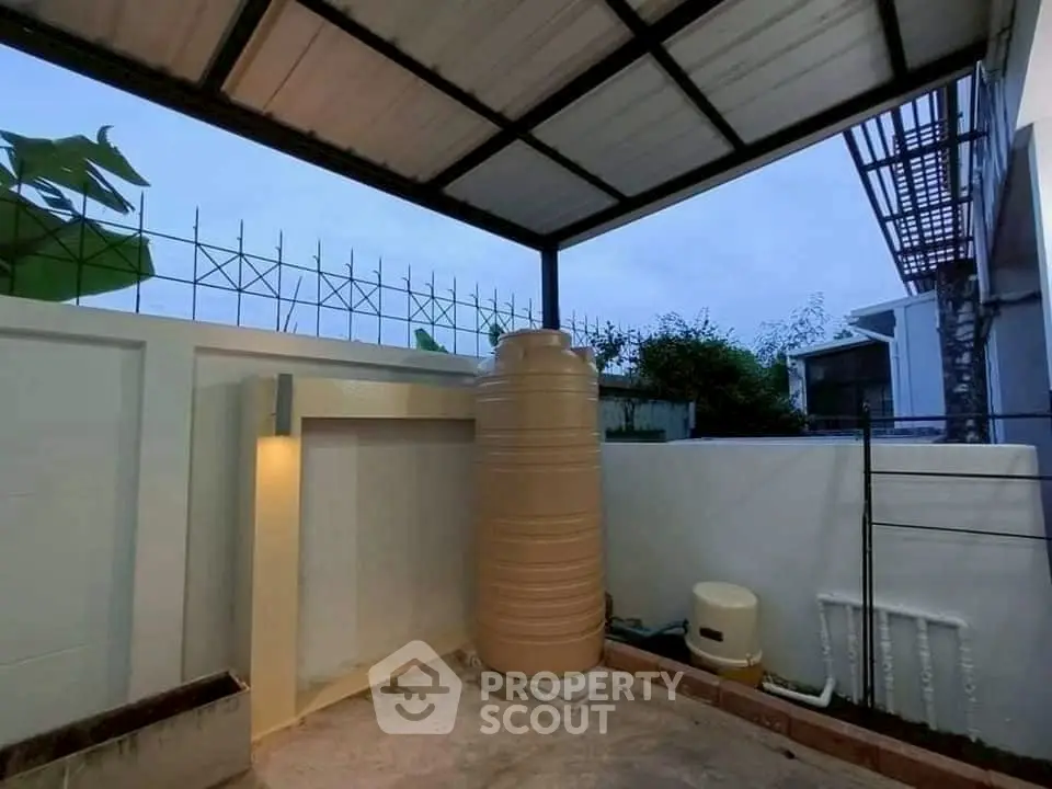 Covered outdoor area with water tank and modern fencing, ideal for utility space.