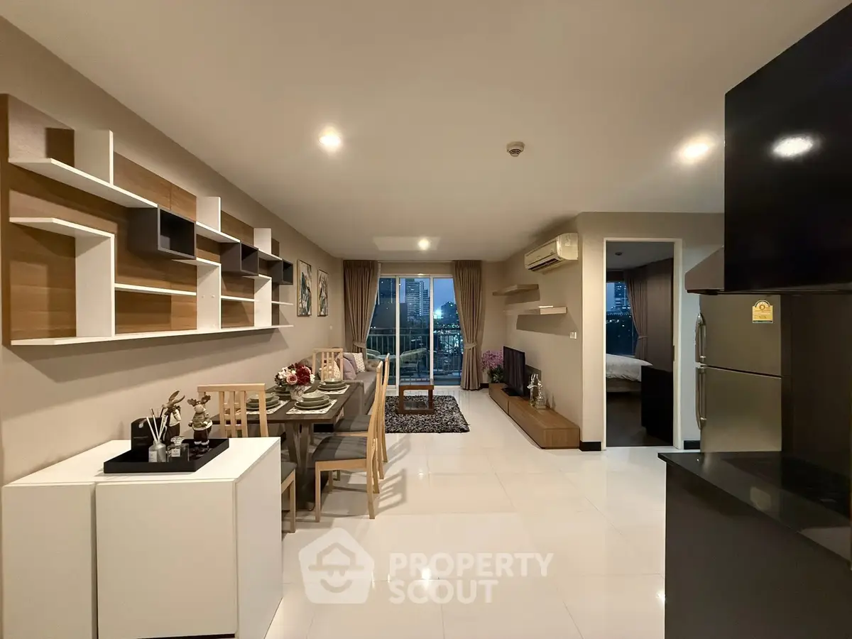 Modern open-plan living room with dining area and city view balcony in stylish apartment.