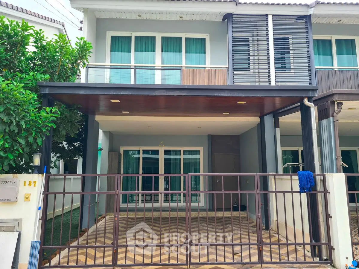 Modern townhouse exterior with gated entrance and balcony, ideal for urban living.
