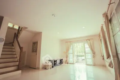 Spacious living room with large windows and staircase, perfect for family gatherings.