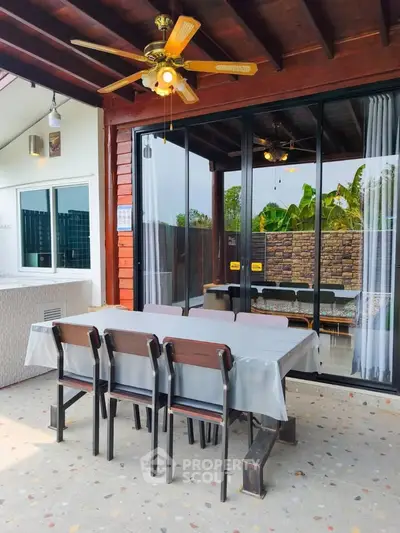 Charming outdoor patio with dining set and ceiling fan, perfect for entertaining guests.