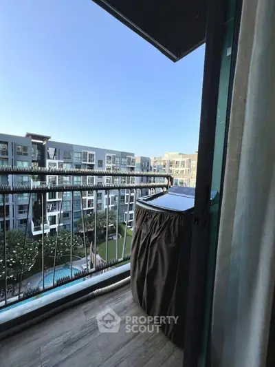 Charming balcony with scenic view of modern apartment complex and lush garden.