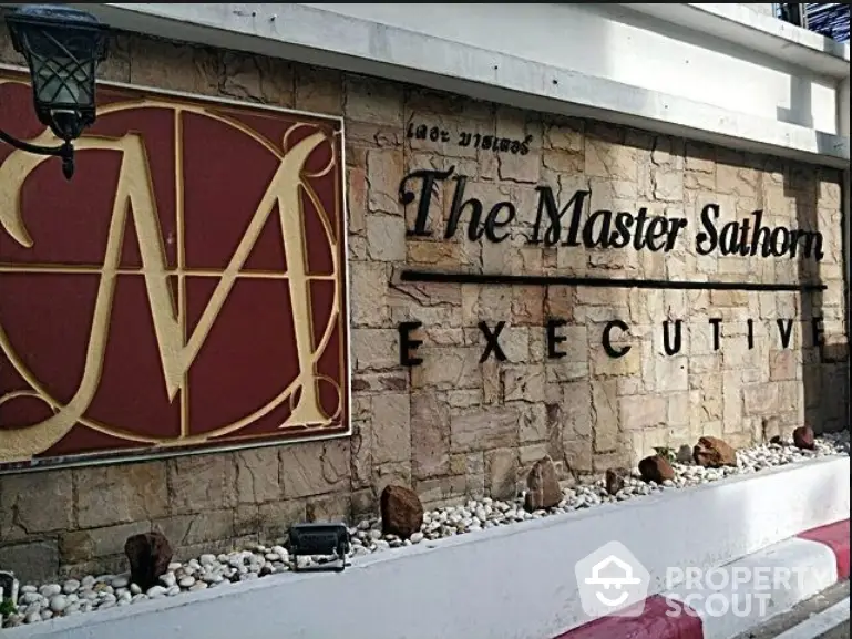 The Master Sathorn Executive building entrance sign with elegant stone wall design.