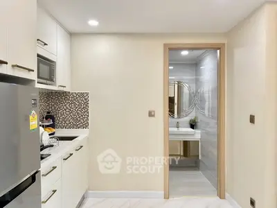 Modern kitchen with sleek cabinetry and adjacent bathroom, featuring stylish mosaic backsplash and stainless steel appliances.