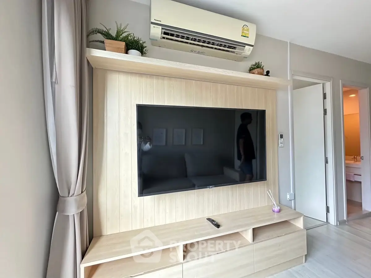 Modern living room with wall-mounted TV and air conditioning unit, featuring sleek wooden cabinetry.