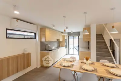 Modern open-plan kitchen and dining area with wooden cabinetry and stylish lighting.