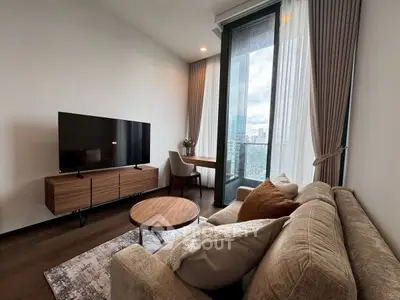 Modern living room with large TV, stylish furniture, and city view from balcony.