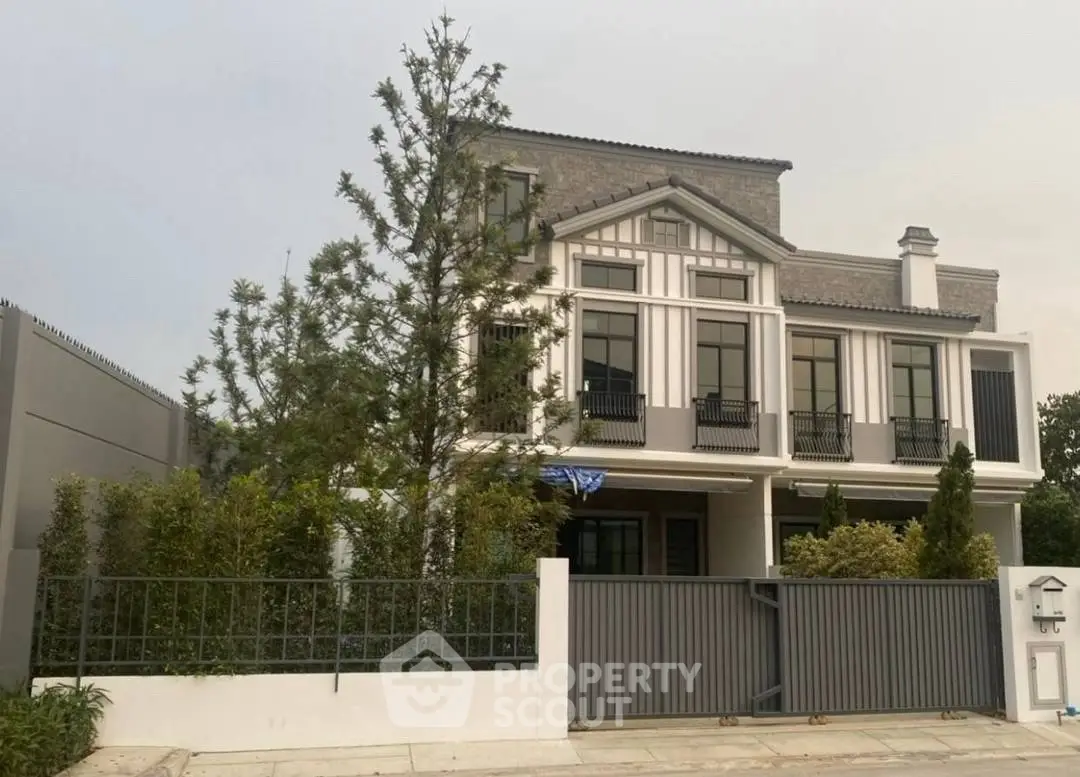 Elegant modern house exterior with lush greenery and secure gated entrance.