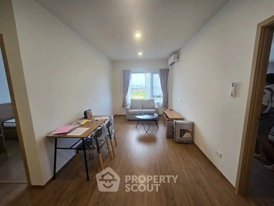 Spacious living room with modern decor and natural light, featuring a cozy seating area and work desk.