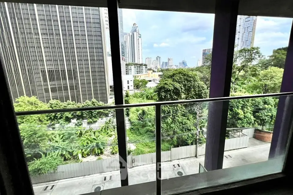 Stunning urban view from a modern balcony overlooking lush greenery and city skyline.