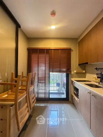 Modern kitchen with wooden cabinets and dining area, featuring sleek design and natural light.