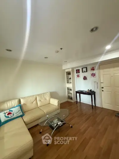 Cozy living room with beige sofa and glass coffee table in modern apartment.