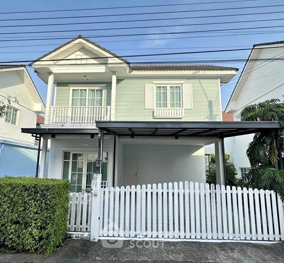 Charming two-story house with white picket fence and lush greenery, perfect for family living.