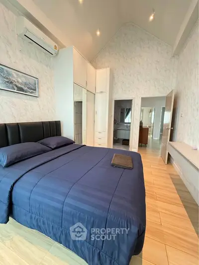 Spacious bedroom with modern decor and high ceiling, featuring a cozy bed and stylish furnishings.