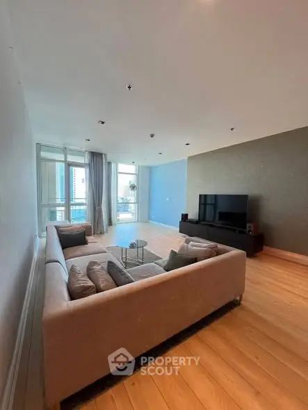 Spacious modern living room with large windows and stylish furniture in a high-rise apartment.