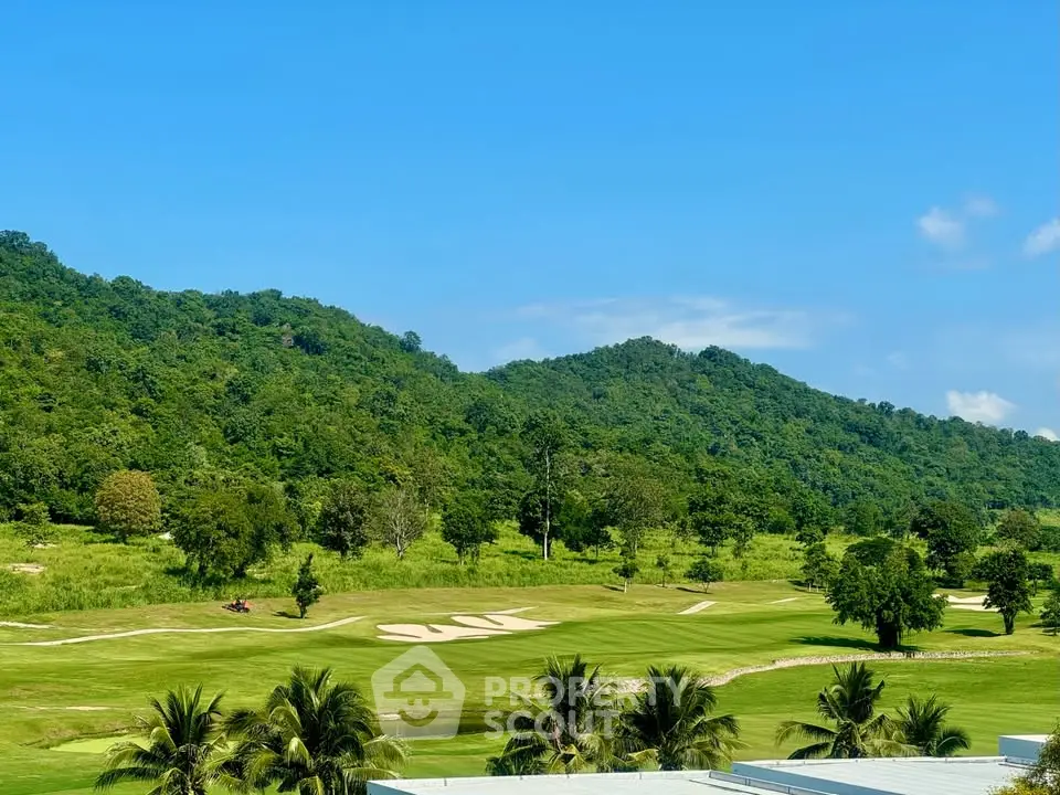 Scenic golf course view with lush greenery and rolling hills under a clear blue sky.