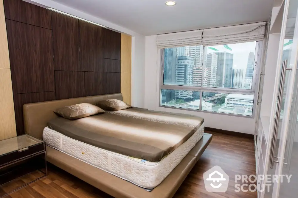 Modern bedroom with city view, featuring a stylish bed and large window for natural light.