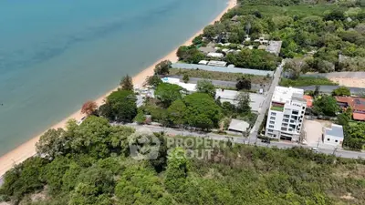 Stunning aerial view of beachfront property with lush greenery and modern buildings, perfect for investment.