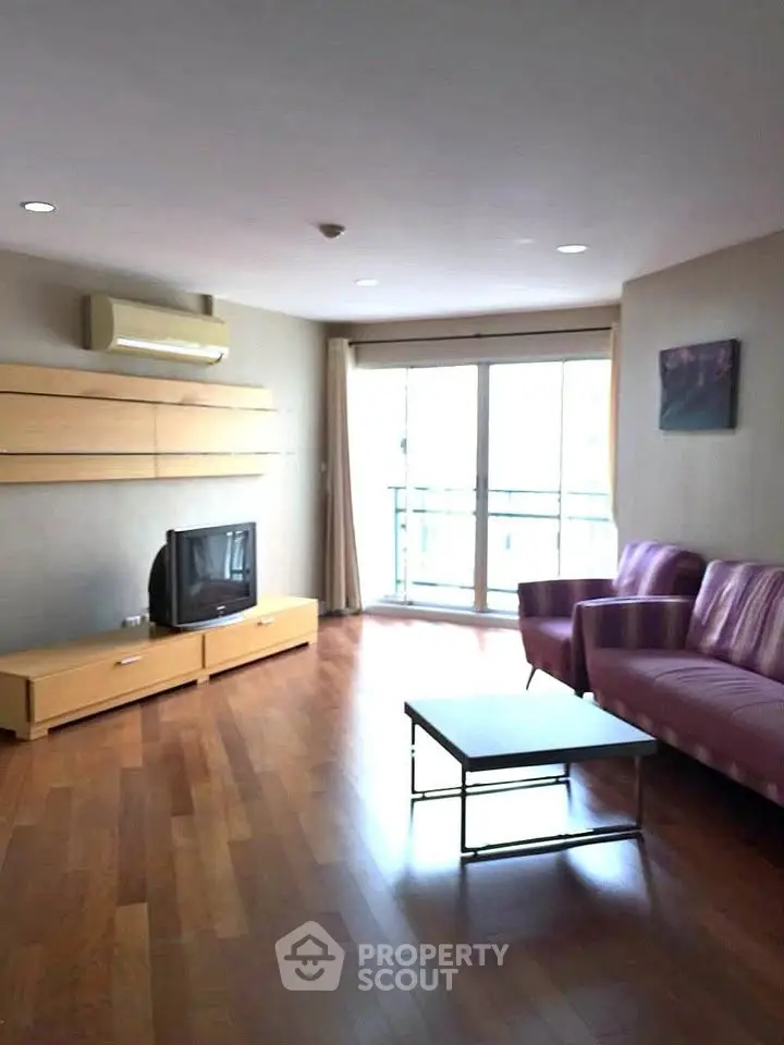 Spacious living room with hardwood floors and modern furniture in a bright apartment.