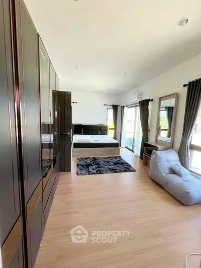 Spacious bedroom with modern furnishings and large windows for natural light.