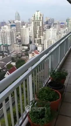Stunning cityscape view from a high-rise balcony with potted plants.