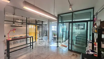 Modern industrial-style office space with glass partitions and concrete flooring