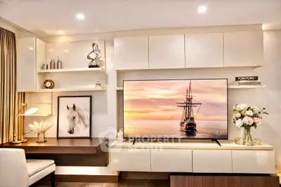 Modern living room with stylish decor and large TV, featuring elegant shelving and a cozy workspace.