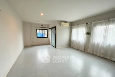 Spacious and bright living room with large windows and air conditioning unit.