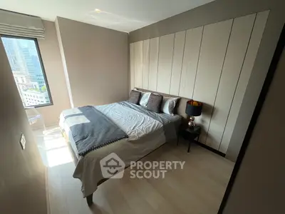 Modern bedroom with large window and stylish decor in urban apartment.