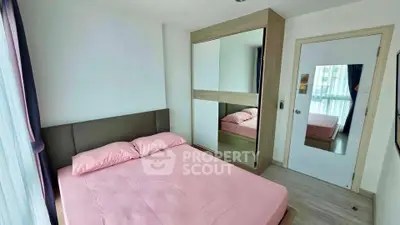 Modern bedroom with pink bedding and mirrored wardrobe in a bright apartment.