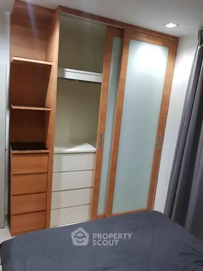 Modern bedroom with built-in wooden wardrobe and sliding glass doors, offering ample storage space.