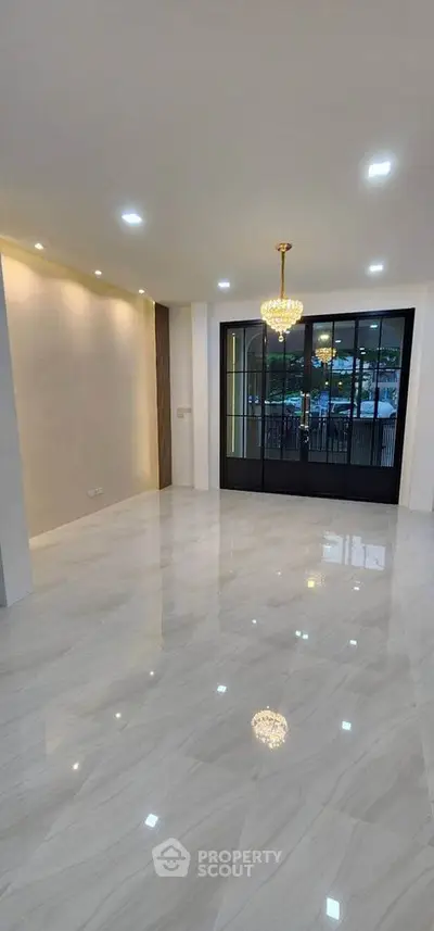 Spacious modern living room with elegant chandelier and large glass doors
