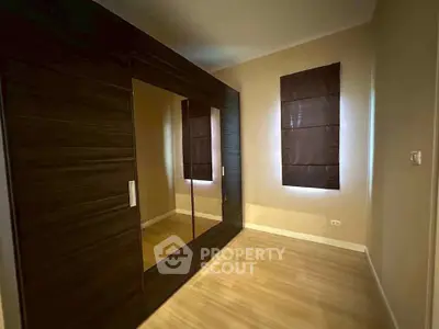 Spacious bedroom with elegant dark wood wardrobe and natural light