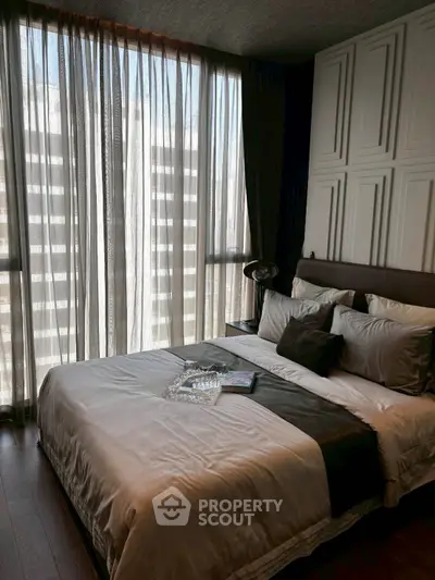 Luxurious bedroom with elegant decor and large window offering natural light in modern apartment.