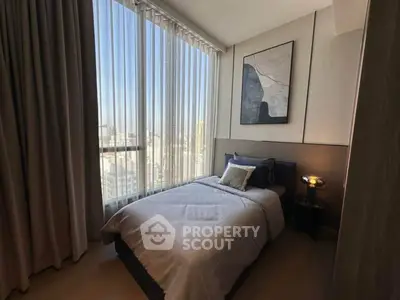 Cozy bedroom with large window offering stunning city views, modern decor, and elegant furnishings.