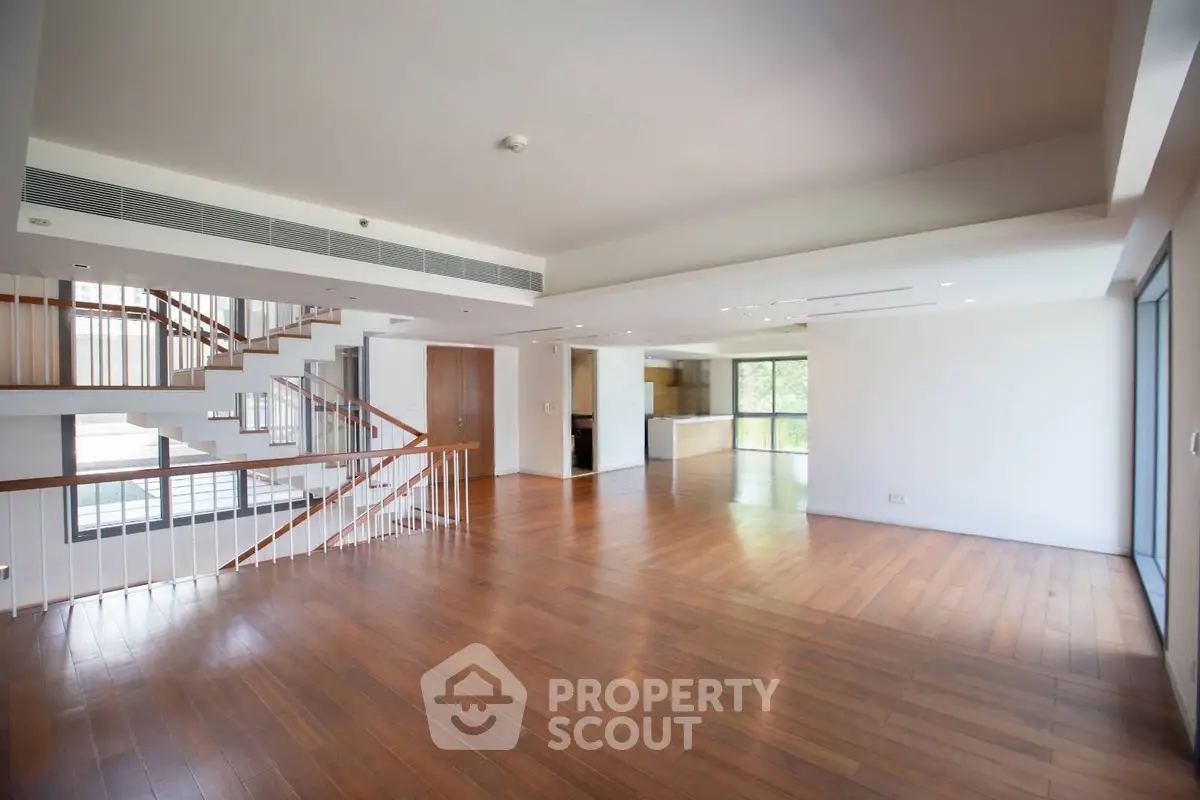 Spacious open-plan living room with wooden flooring and modern staircase in luxury home.