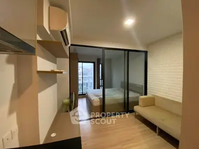 Modern studio apartment with glass partition, cozy sofa, and city view.