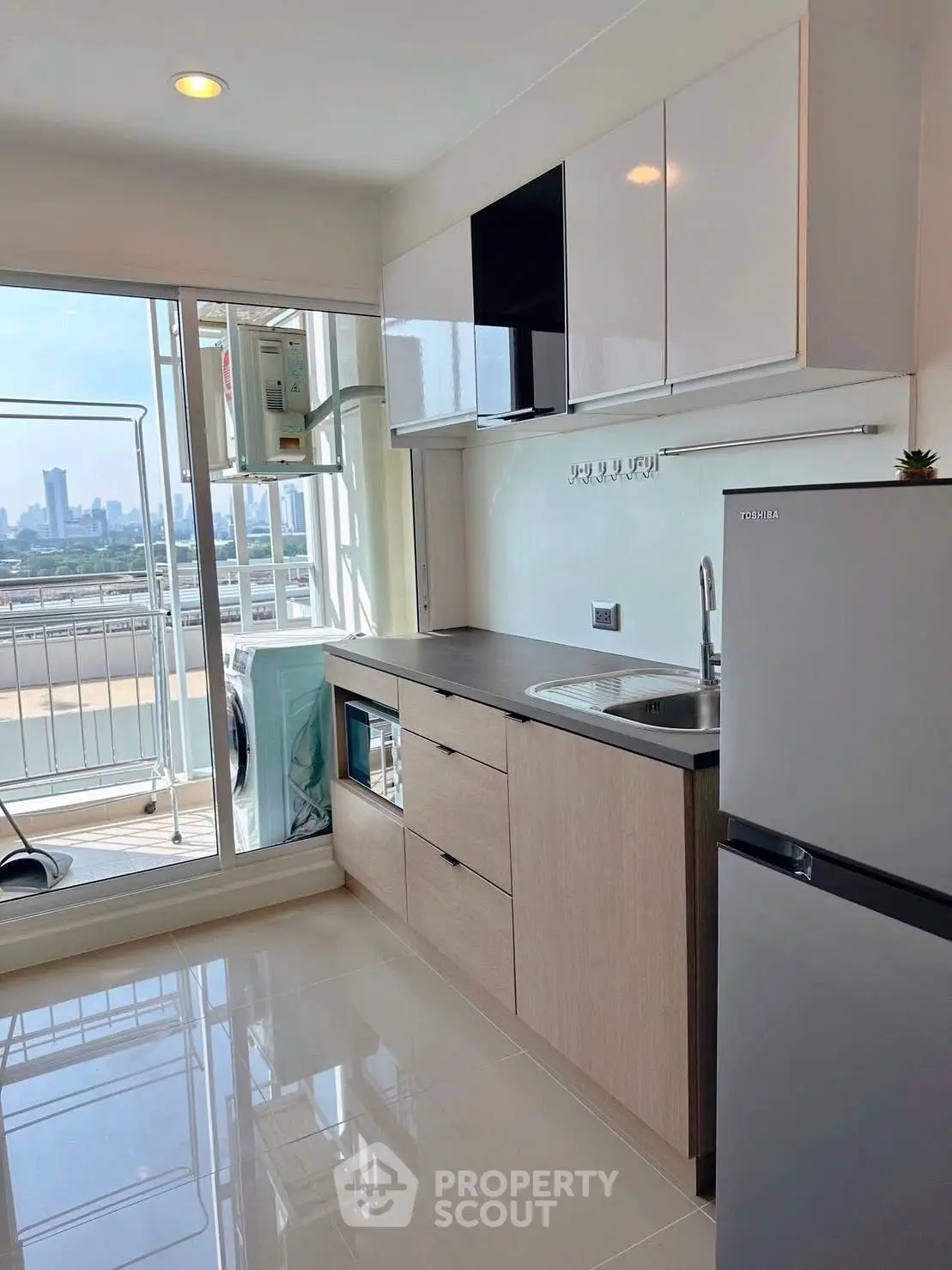 Modern kitchen with city view, sleek cabinetry, and stainless steel appliances