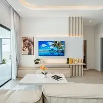 Modern living room with stylish decor and large TV, featuring elegant lighting and cozy seating.