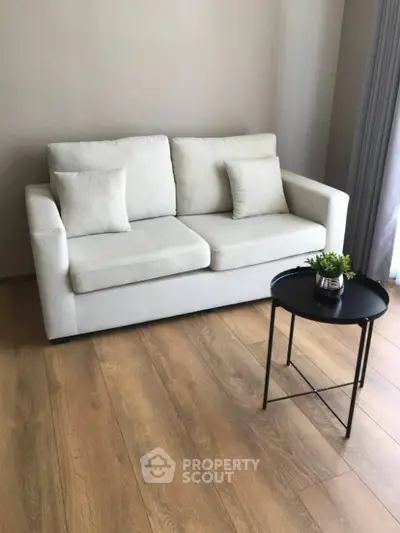 Cozy living room with modern white sofa and stylish round coffee table on wooden floor.