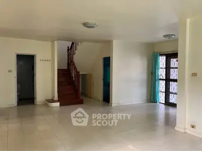 Spacious open-plan living area with staircase and natural light, ideal for modern living.